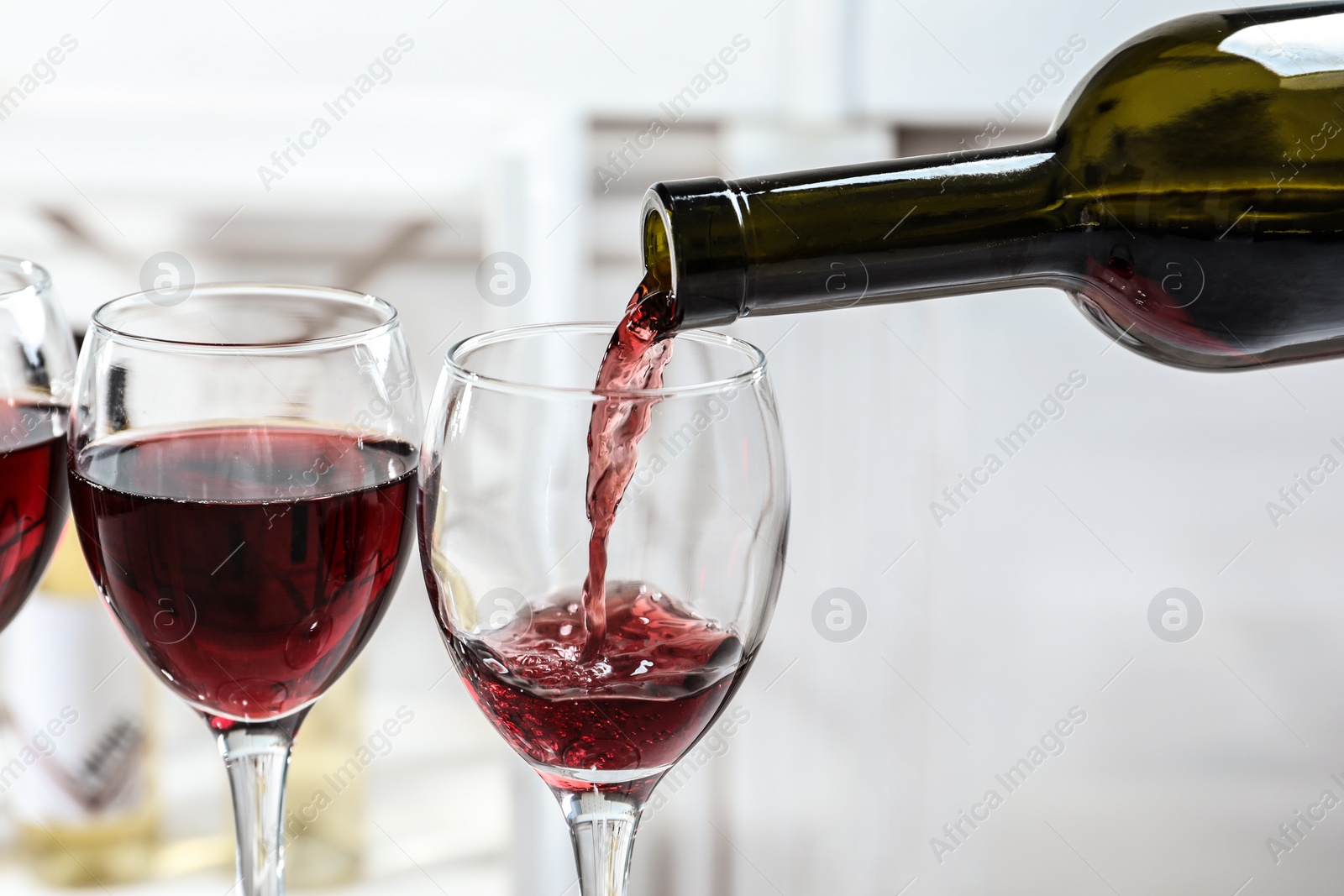 Photo of Pouring delicious red wine into glass on light background