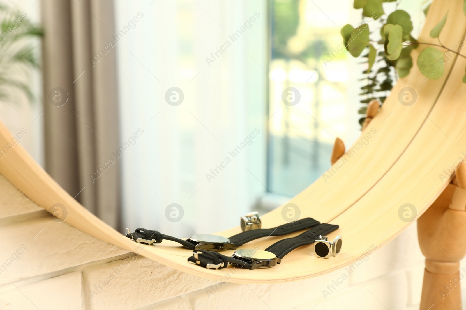 Photo of Round mirror with male accessories on brick wall indoors, closeup. Interior design