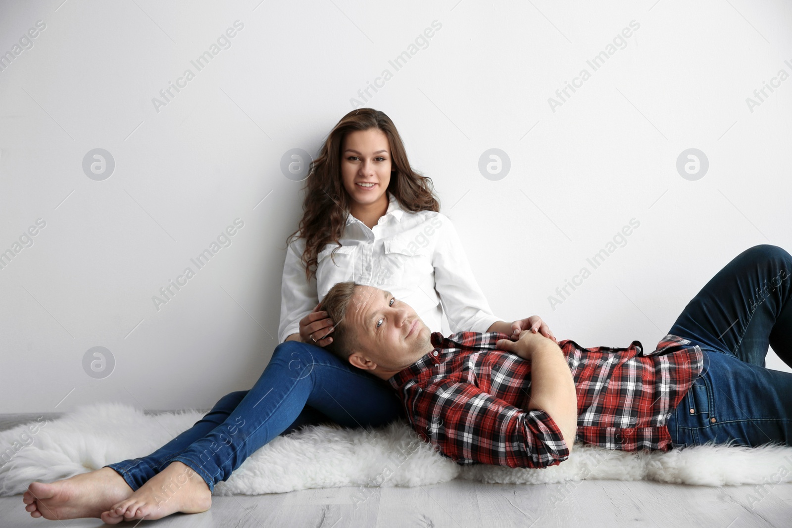 Photo of Cute happy couple near white wall. Space for text