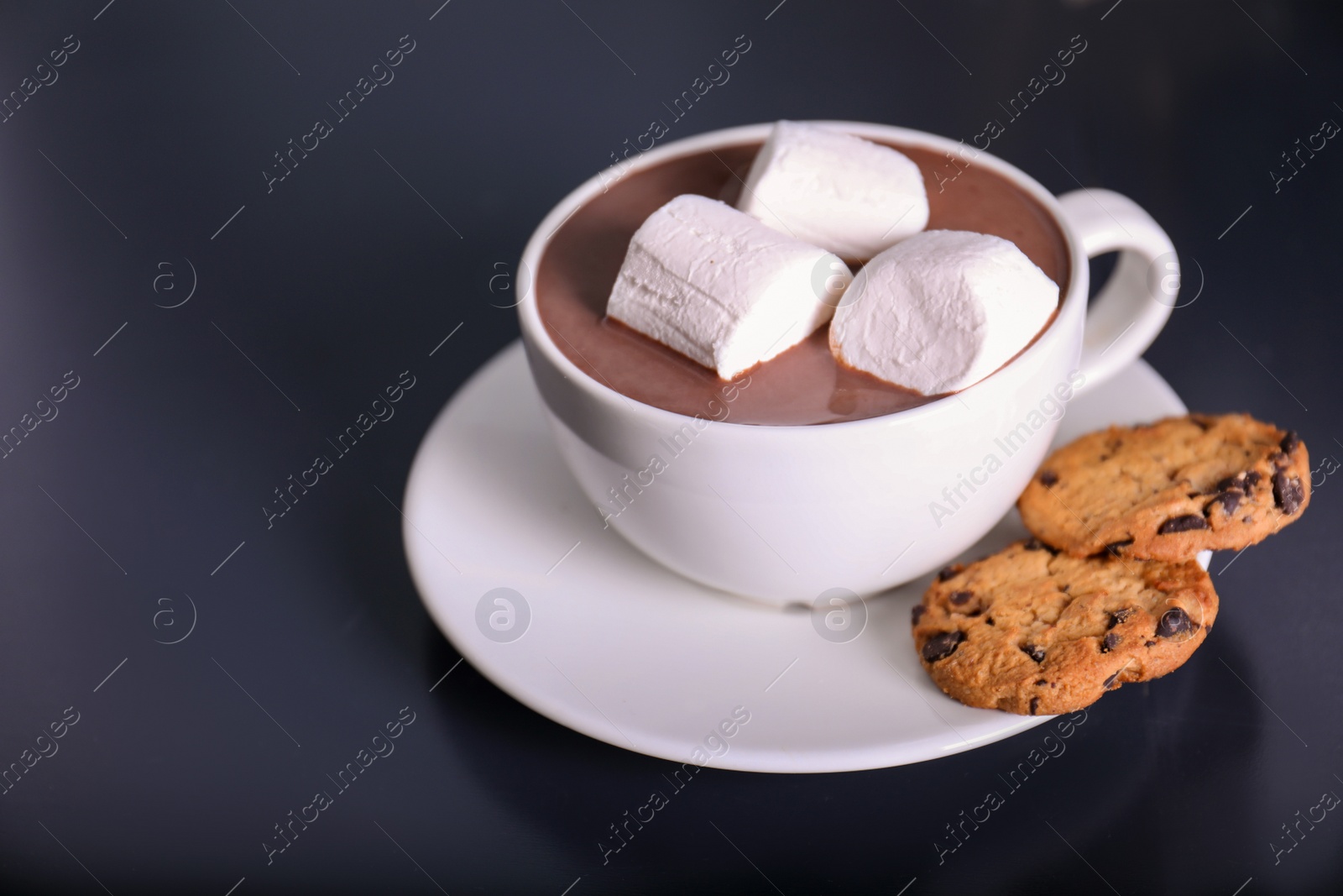 Photo of Cup of aromatic cacao with marshmallows and cookies on dark table. Space for text