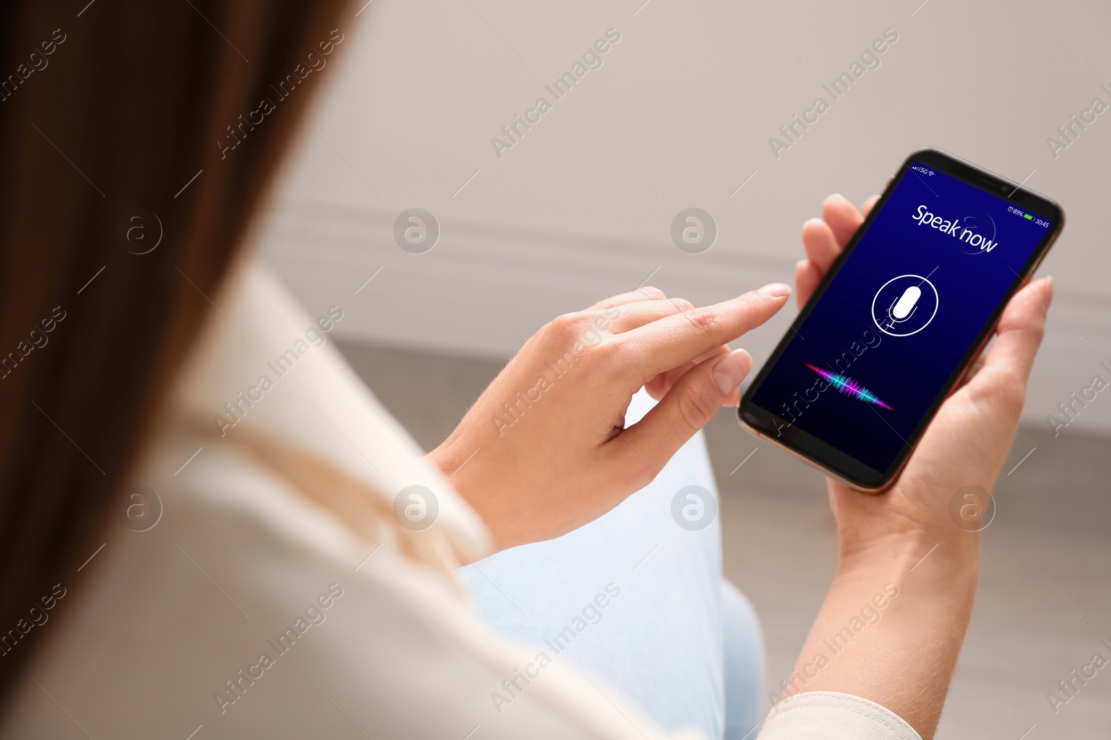 Image of Woman using voice search on smartphone indoors, closeup