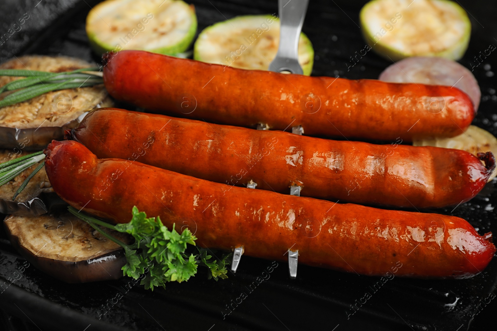 Photo of Delicious grilled sausages and vegetables   in grill pan, closeup