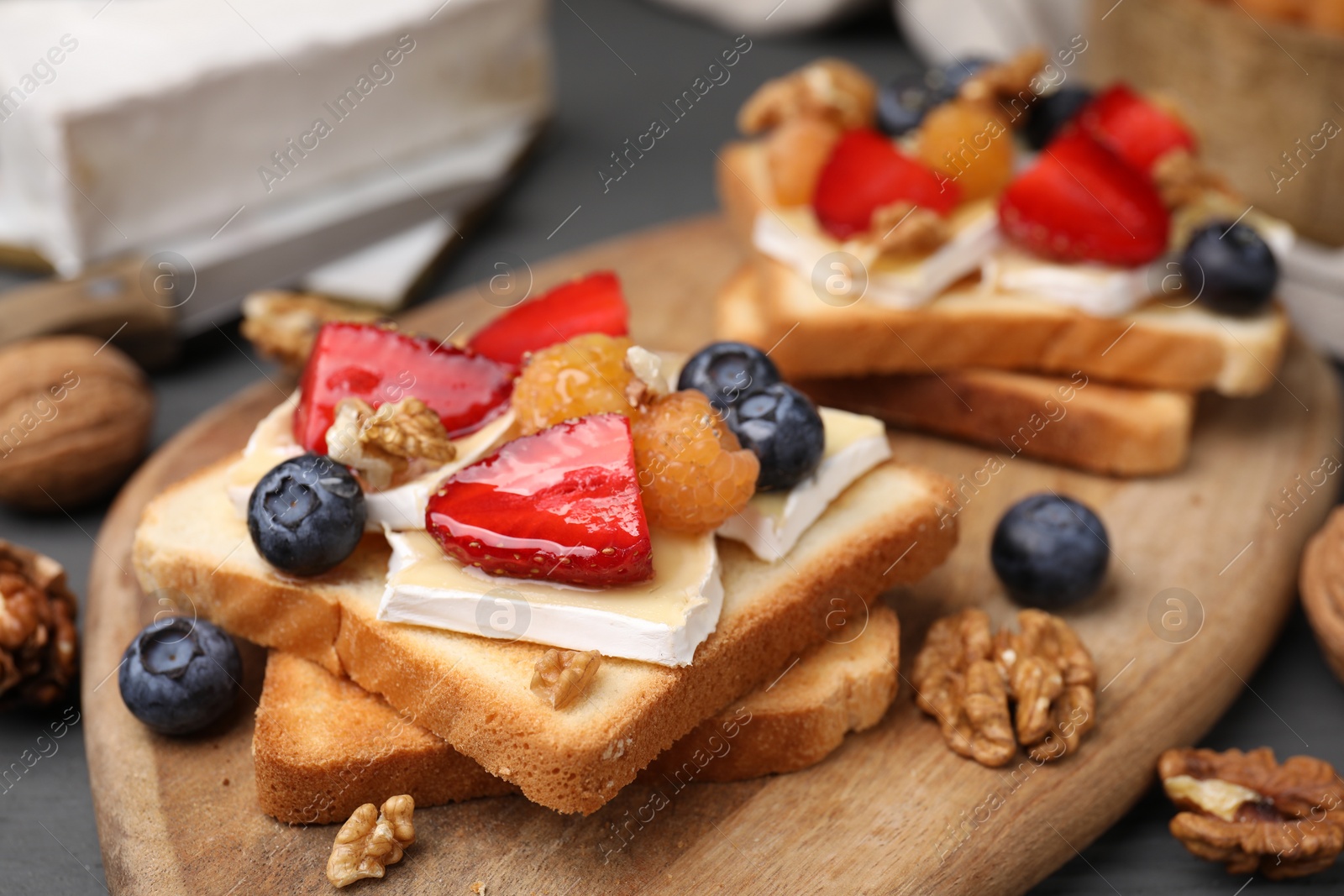 Photo of Tasty sandwiches with brie cheese, fresh berries and walnuts on table, closeup