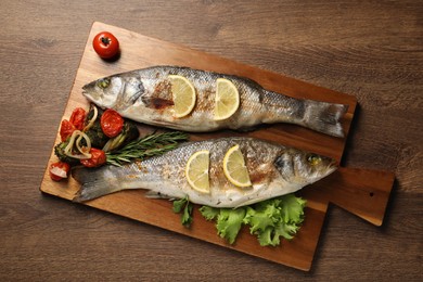 Photo of Delicious baked fish and vegetables on wooden table, top view