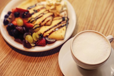 Cup of aromatic coffee and delicious desserts on wooden table, closeup