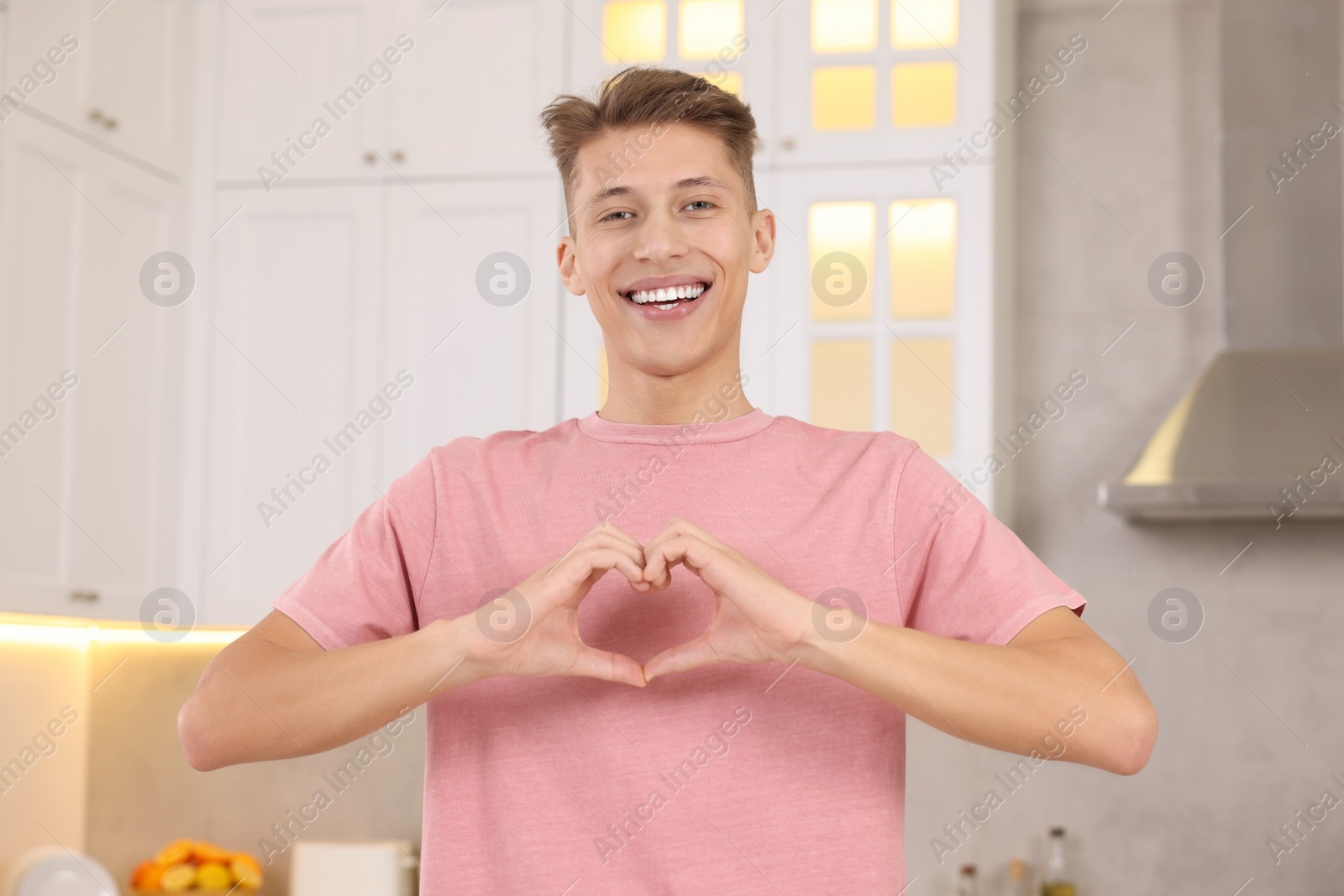 Photo of Happy man showing heart gesture with hands at home