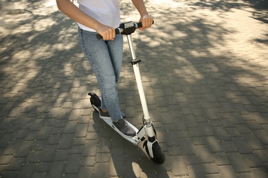 Photo of Woman riding electric kick scooter outdoors. Space for text