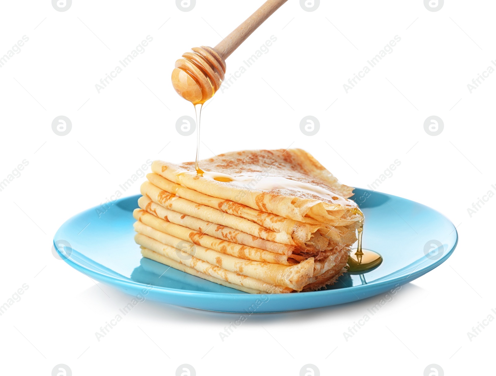 Photo of Pouring honey onto tasty thin folded pancakes on plate against white background