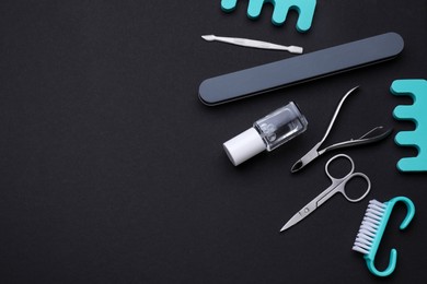 Set of pedicure tools on black background, flat lay. Space for text