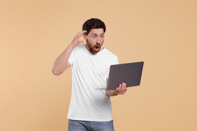 Photo of Emotional man with laptop on beige background. Space for text