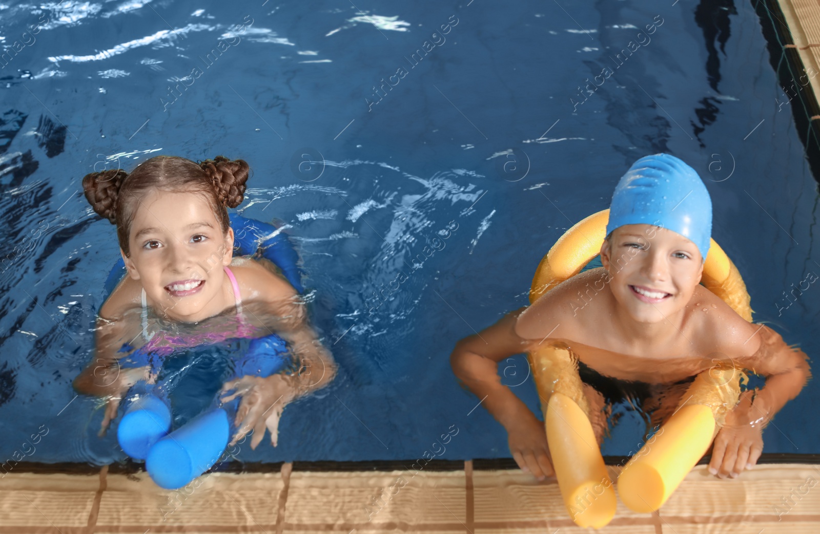 Photo of Little kids with swimming noodles in indoor pool