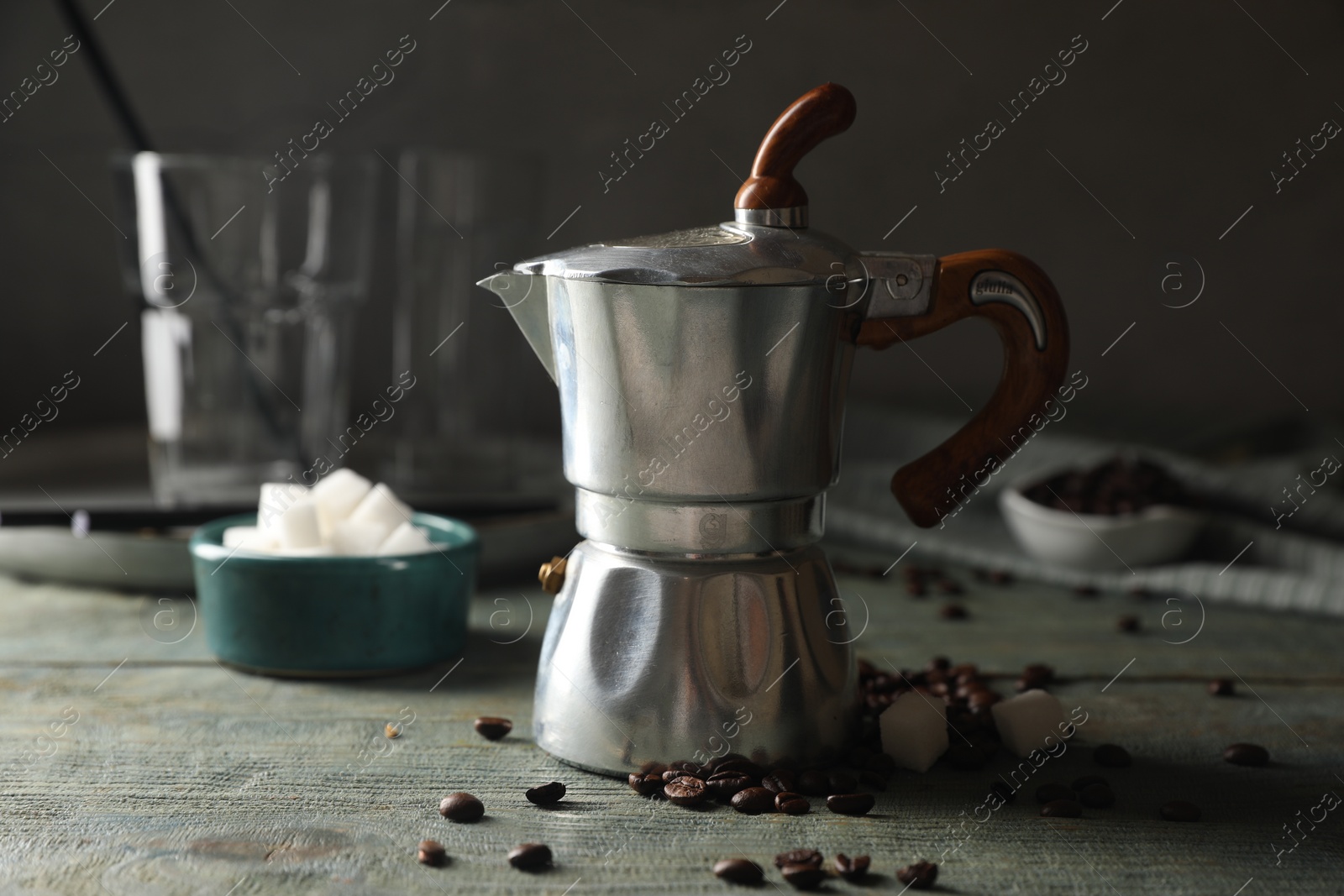 Photo of Moka pot, coffee beans and sugar cubes on rustic wooden table