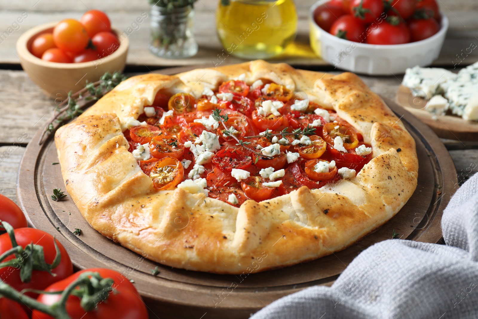 Photo of Tasty galette with tomato, thyme and cheese (Caprese galette) on wooden table, closeup