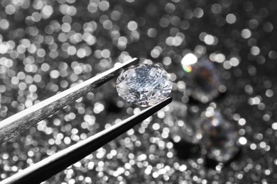 Tweezers with beautiful diamond on dark shiny background, closeup