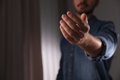 Man offering helping hand on blurred background, closeup. Space for text