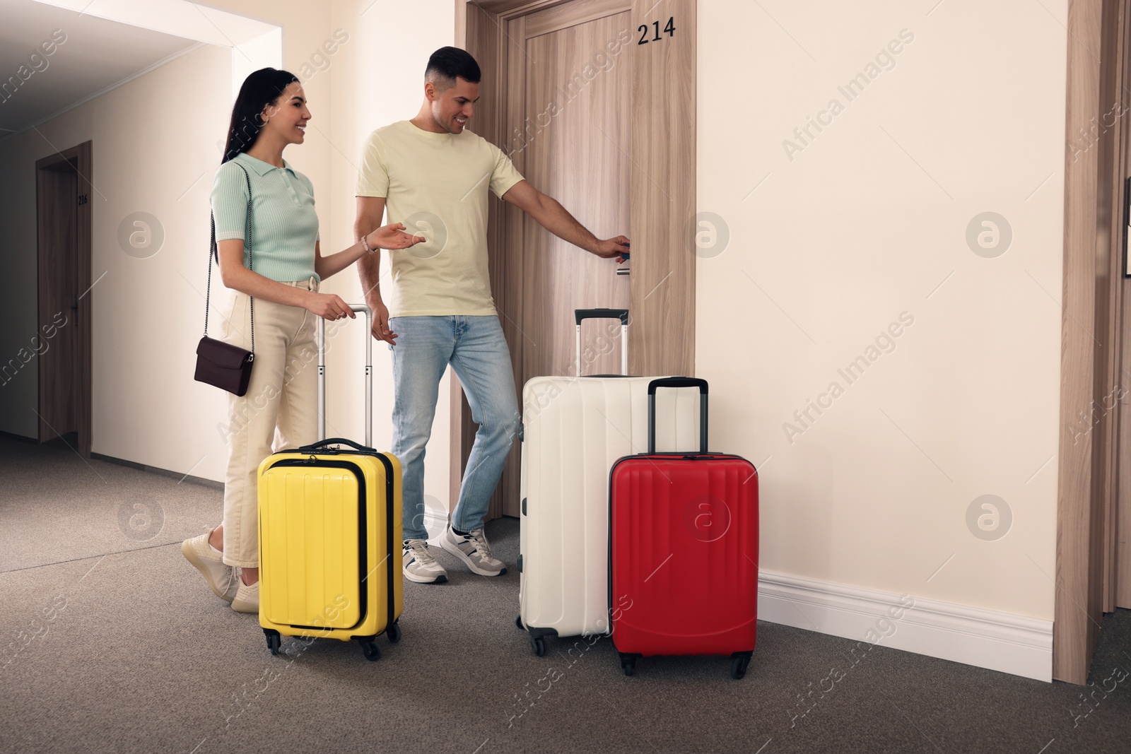 Photo of Happy couple opening magnetic door lock with key card in hotel