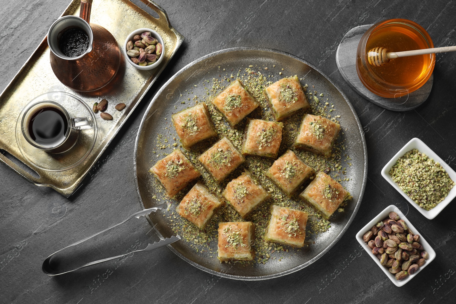 Photo of Delicious fresh baklava with chopped nuts served on grey table, flat lay. Eastern sweets