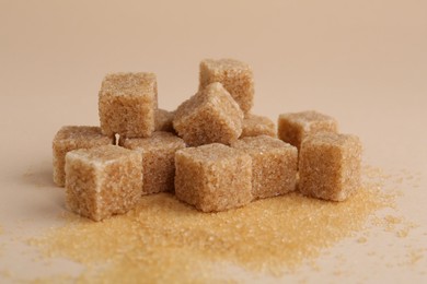 Photo of Pile of brown sugar cubes on beige background, closeup