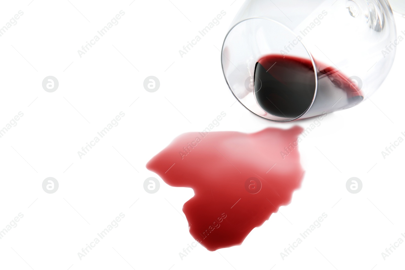 Photo of Transparent glass and spilled exquisite red wine on white background