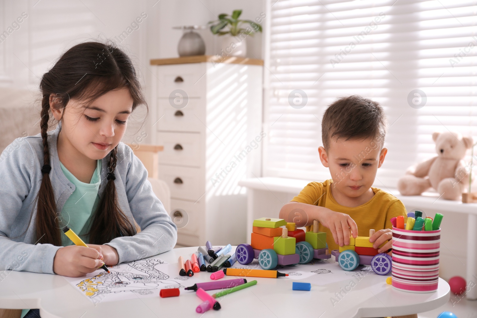 Photo of Cute children coloring drawing and playing at table in room