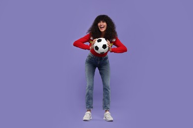 Photo of Happy fan holding soccer ball on violet background