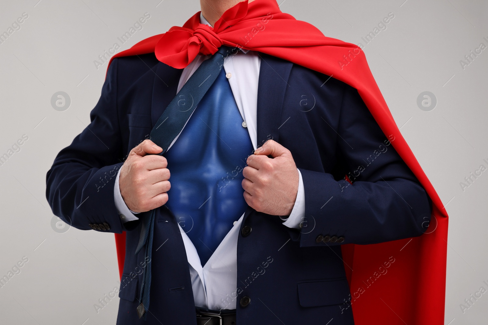 Image of Businessman wearing superhero costume under suit on light grey background, closeup