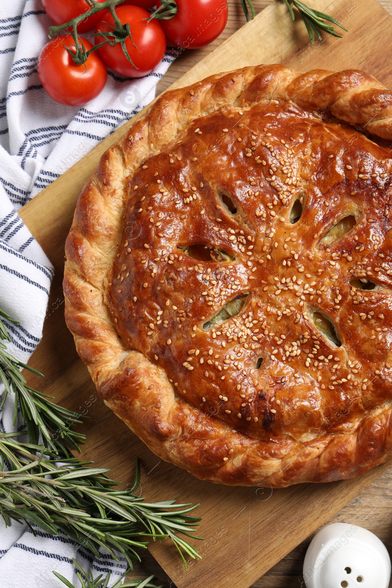 Photo of Tasty homemade pie, rosemary and tomatoes on wooden table, flat lay