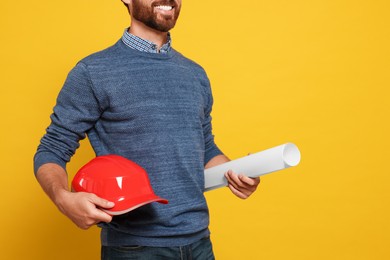 Photo of Professional engineer with hard hat and draft on yellow background, closeup