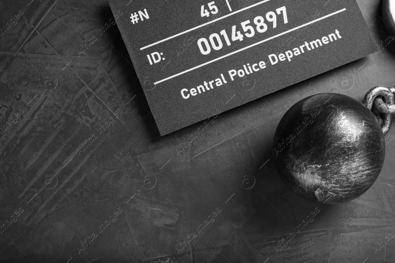 Photo of Metal ball with chain and mugshot letter board on grey table, flat lay. Space for text