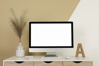 Photo of Modern computer, decor and office supplies on white wooden table near color wall