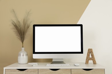 Modern computer, decor and office supplies on white wooden table near color wall