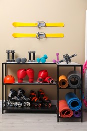 Many different sports equipment in room with beige walls