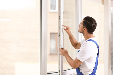 Construction worker repairing plastic window with screwdriver indoors