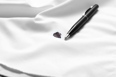 Photo of Pen and stain of black ink on white shirt, closeup. Space for text