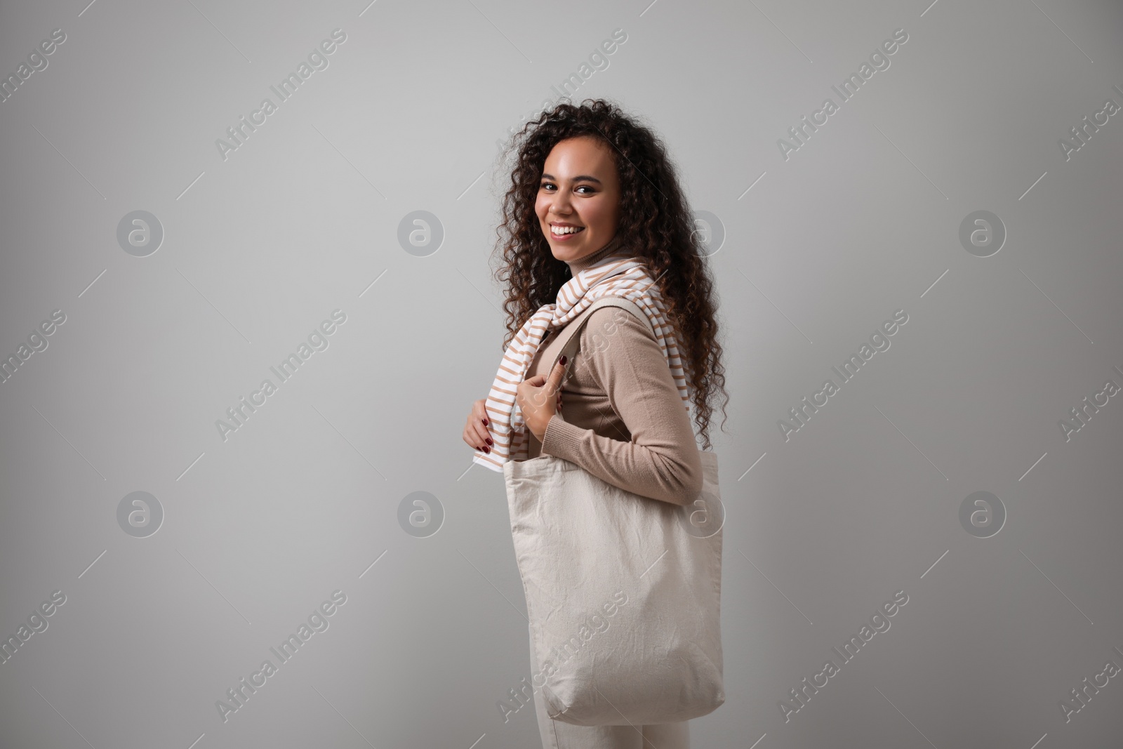 Photo of Happy African-American woman with eco bag on grey background