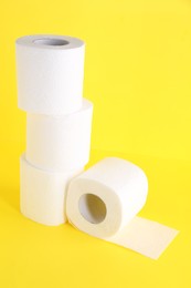 Many soft toilet paper rolls on yellow background