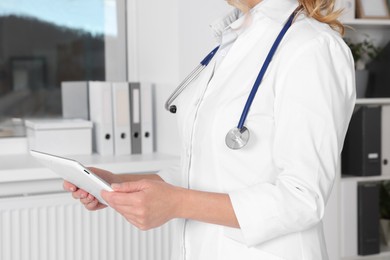 Photo of Doctor with tablet and stethoscope in clinic, closeup. Online medicine concept