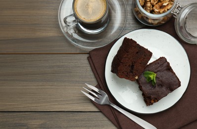 Photo of Delicious brownies served with walnuts and coffee on wooden table, flat lay. Space for text