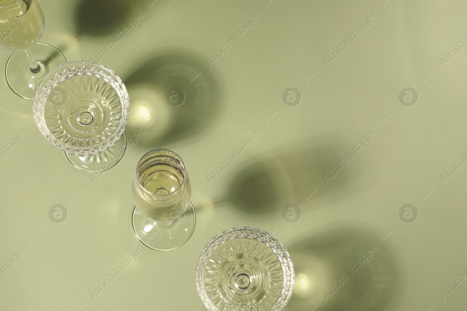 Photo of Glasses of delicious sparkling wine on light yellow background, above view. Space for text