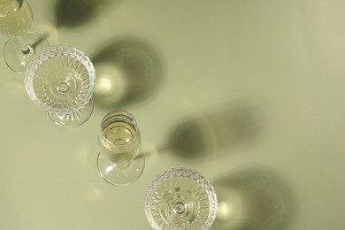 Glasses of delicious sparkling wine on light yellow background, above view. Space for text