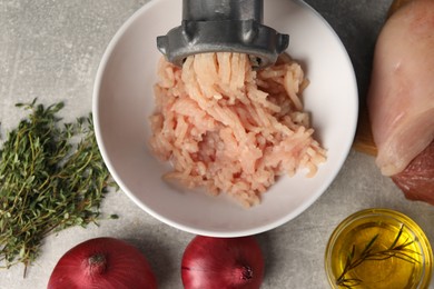 Photo of Metal meat grinder with chicken mince and different products on light grey table, flat lay