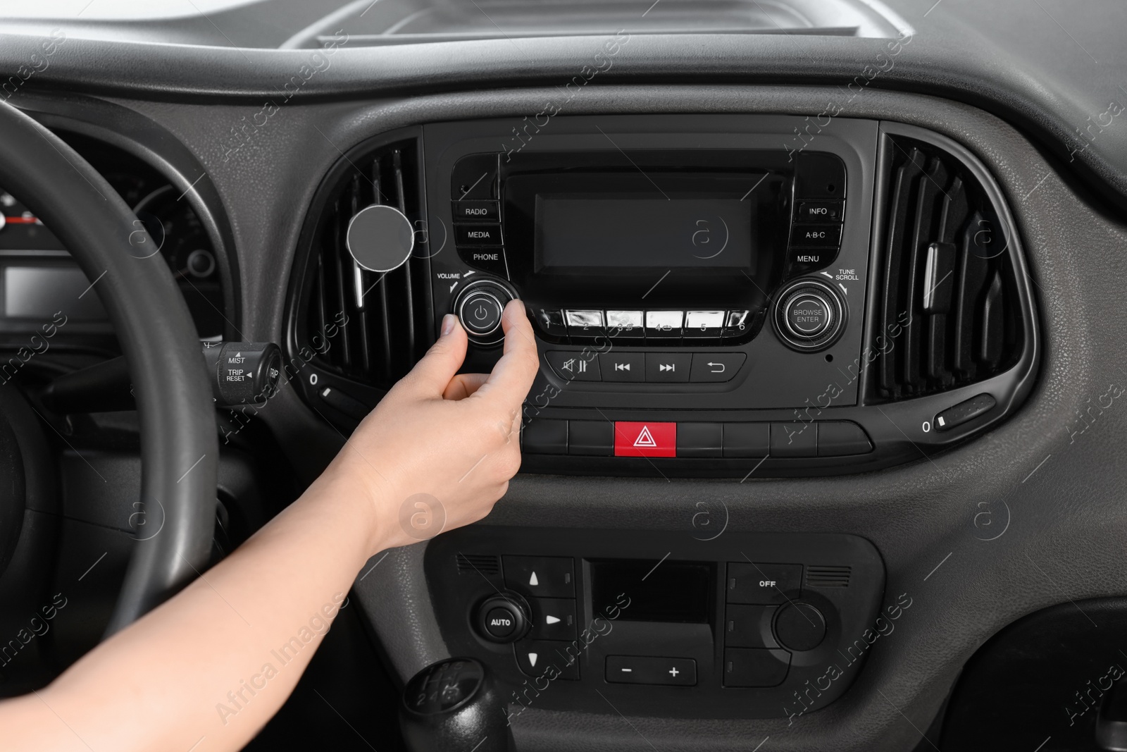 Photo of Listening to radio while driving. Woman turning volume button on vehicle audio in car, closeup