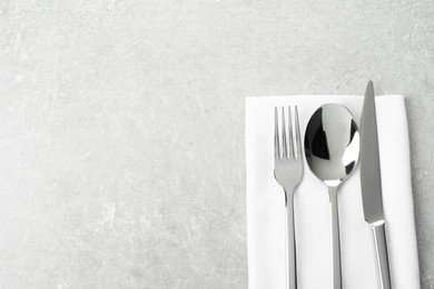 Photo of Stylish cutlery set and napkin on grey table, top view. Space for text