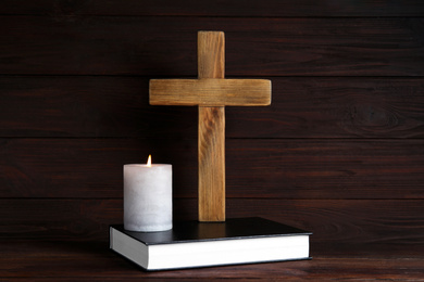 Cross, Bible and burning candle on wooden background. Christian religion