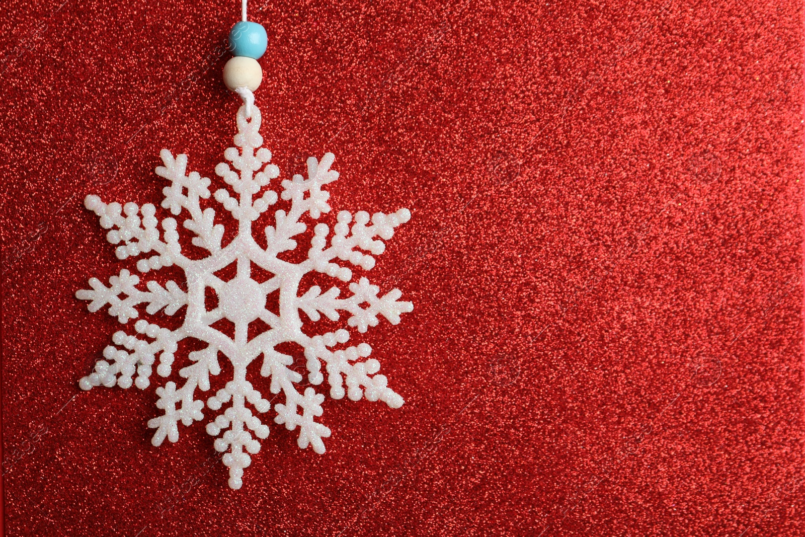 Photo of Beautiful decorative snowflake on sparkling red glitter background, closeup. Space for text