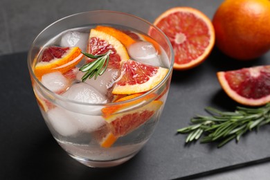 Photo of Delicious refreshing drink with sicilian orange and rosemary near fresh ingredients on grey table, closeup