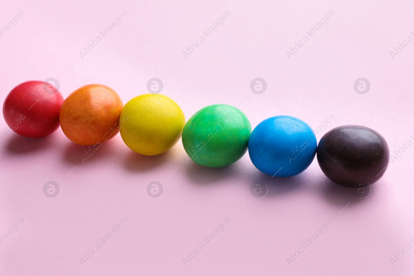 Photo of Colorful candies on pink background. Rainbow palette