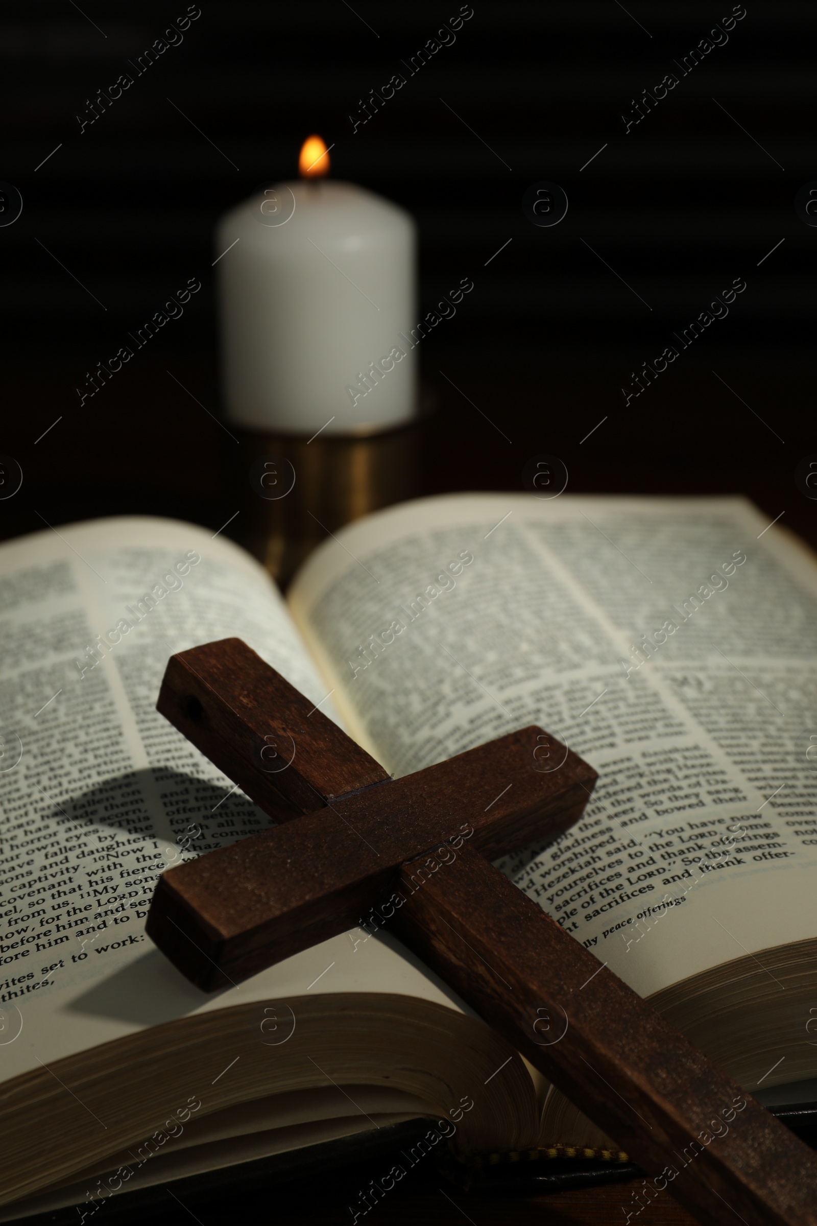 Photo of Wooden cross, Bible and church candle on table