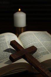 Photo of Wooden cross, Bible and church candle on table