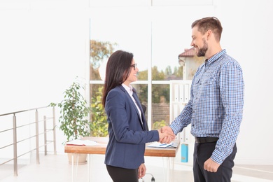 Human resources manager shaking hands with applicant during job interview in office